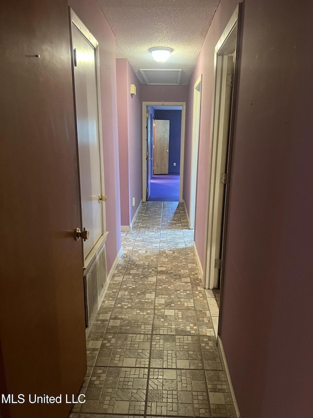2285 Harkness Ct, Biloxi, MS 39532 - hall featuring a textured ceiling, baseboards, brick patterned flooring, and attic access