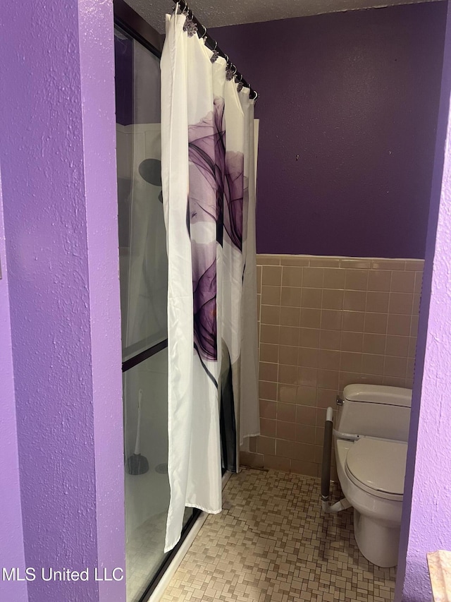 2285 Harkness Ct, Biloxi, MS 39532 - full bathroom with a stall shower, toilet, tile walls, and a wainscoted wall