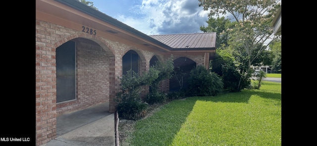 2285 Harkness Ct, Biloxi, MS 39532 - view of exterior entry featuring a lawn, brick siding, and metal roof