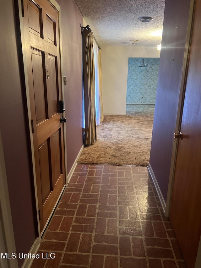 2285 Harkness Ct, Biloxi, MS 39532 - hall with baseboards, dark colored carpet, a textured ceiling, and brick floors