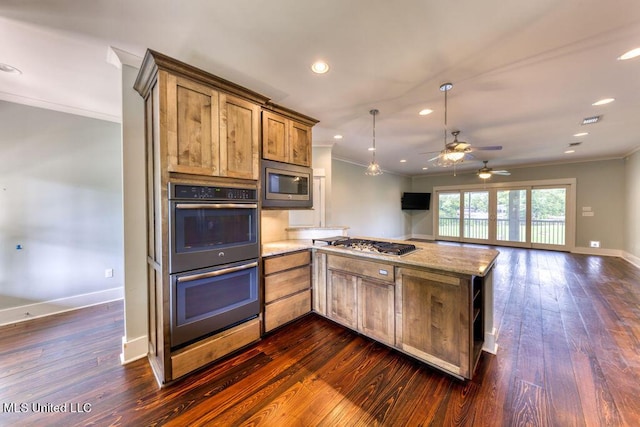 kitchen featuring light stone countertops, ornamental molding, stainless steel appliances, ceiling fan, and hanging light fixtures