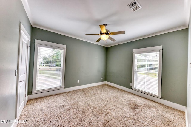 spare room featuring carpet flooring, ceiling fan, a healthy amount of sunlight, and ornamental molding