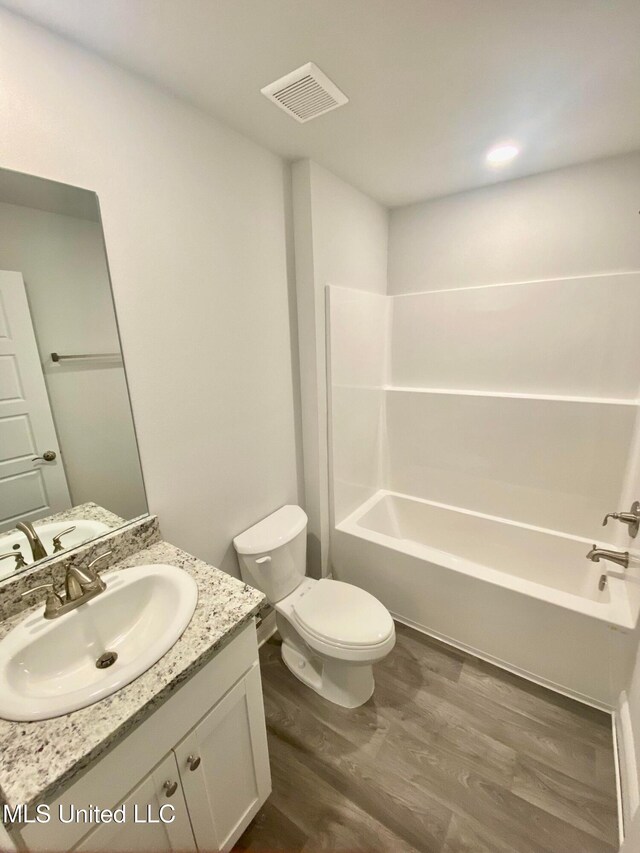 full bathroom featuring bathtub / shower combination, wood-type flooring, vanity, and toilet