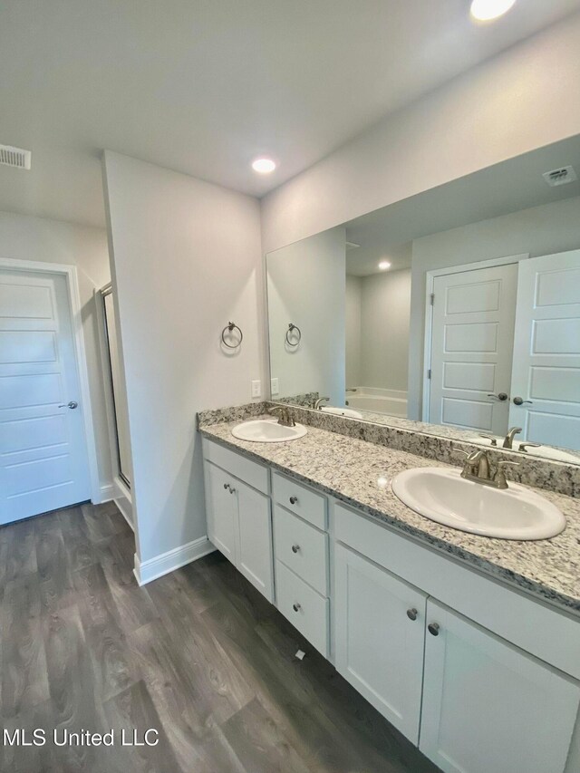 bathroom featuring hardwood / wood-style floors, vanity, and a shower with door