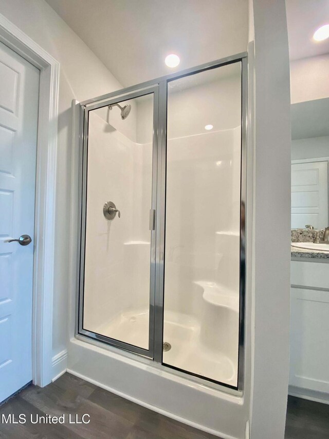 bathroom with a shower with door, vanity, and hardwood / wood-style flooring