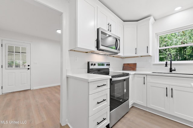 3917 Wildwood Rd, Moss Point, MS 39562 - kitchen with stainless steel appliances, light countertops, light wood-style flooring, white cabinets, and recessed lighting