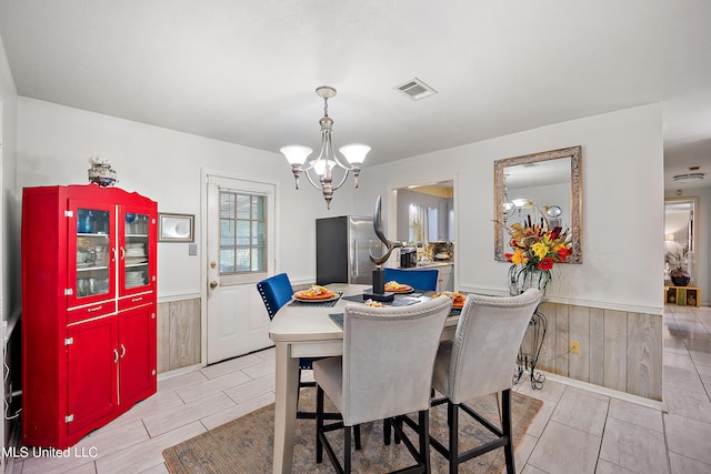 dining space with a notable chandelier and wood walls