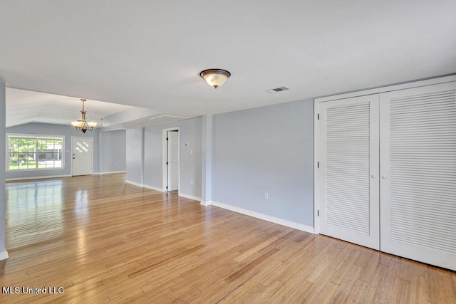 interior space featuring an inviting chandelier, lofted ceiling, and light hardwood / wood-style flooring