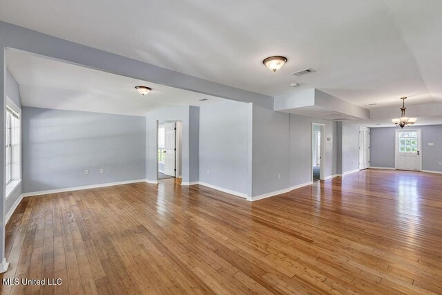 spare room with an inviting chandelier and light hardwood / wood-style flooring