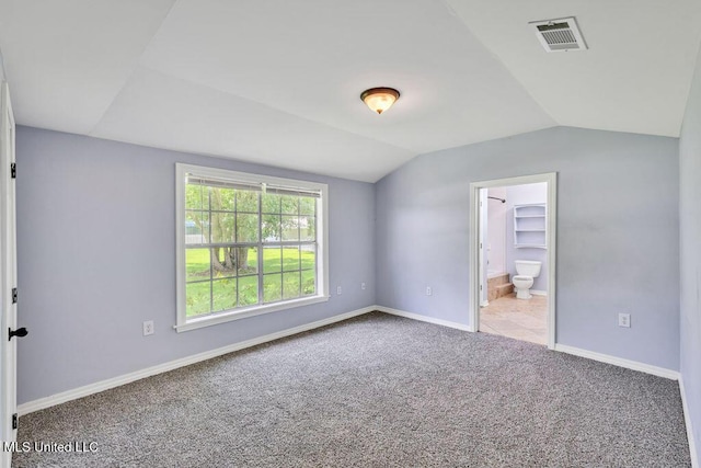 unfurnished bedroom featuring light colored carpet, lofted ceiling, and connected bathroom