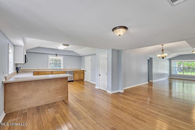 kitchen featuring light hardwood / wood-style floors, appliances with stainless steel finishes, kitchen peninsula, and vaulted ceiling