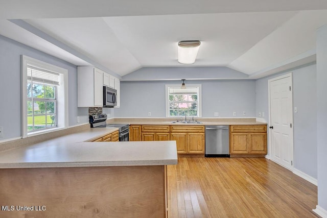 kitchen featuring stainless steel appliances, lofted ceiling, sink, and kitchen peninsula