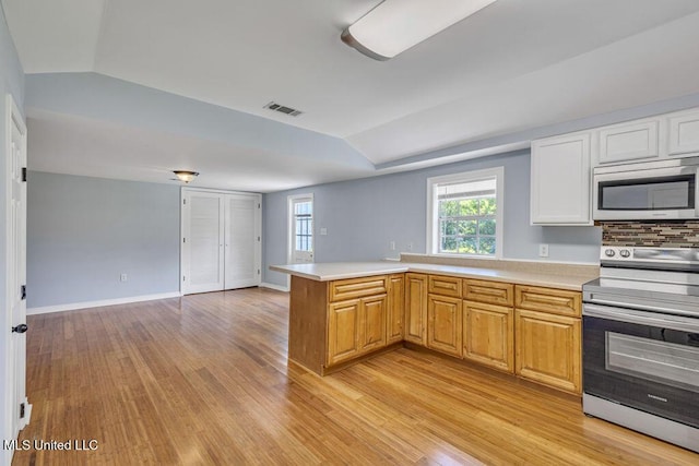 kitchen featuring appliances with stainless steel finishes, lofted ceiling, light hardwood / wood-style floors, and kitchen peninsula