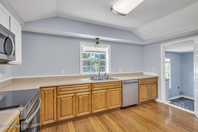 kitchen featuring sink, decorative light fixtures, vaulted ceiling, light hardwood / wood-style flooring, and stainless steel appliances