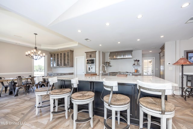 kitchen featuring light stone counters, glass insert cabinets, a large island with sink, and stainless steel appliances