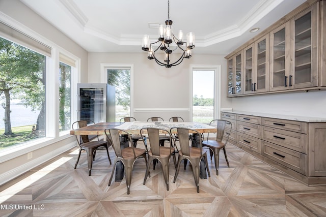 dining area featuring baseboards, ornamental molding, a raised ceiling, and a notable chandelier