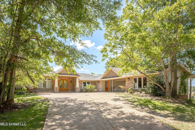 ranch-style house featuring a shingled roof, french doors, and driveway