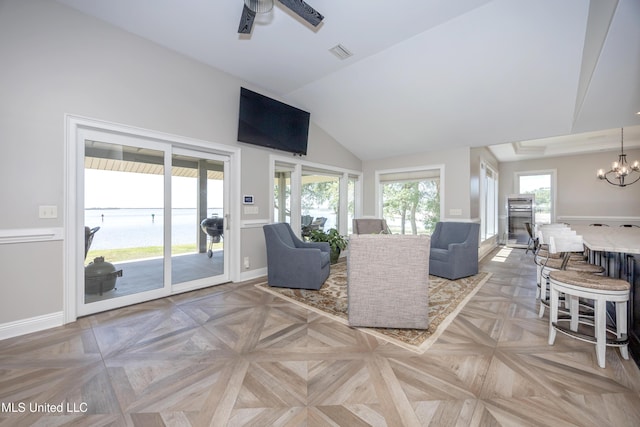 living room with baseboards, visible vents, lofted ceiling, and ceiling fan with notable chandelier