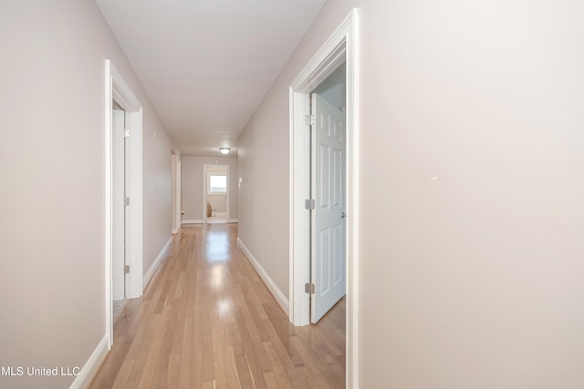hall featuring baseboards and light wood-type flooring
