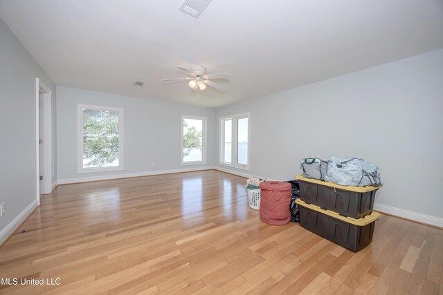 empty room featuring baseboards, ceiling fan, a wealth of natural light, and light wood-style flooring