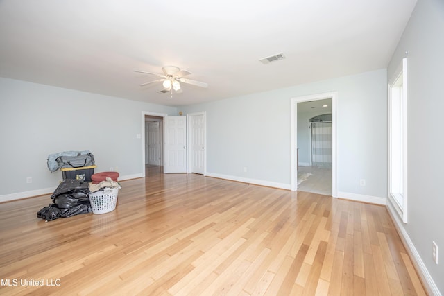 interior space with baseboards, a ceiling fan, light wood-style flooring, and visible vents