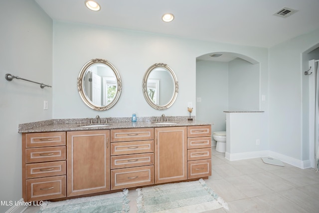 bathroom with double vanity, a sink, tile patterned flooring, and toilet