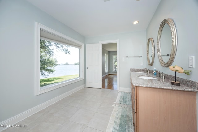 bathroom with tile patterned flooring, vanity, recessed lighting, baseboards, and a water view