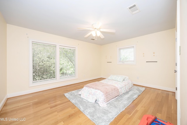bedroom featuring visible vents, a ceiling fan, baseboards, and wood finished floors