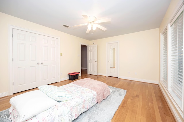 bedroom with visible vents, a closet, baseboards, ceiling fan, and light wood finished floors