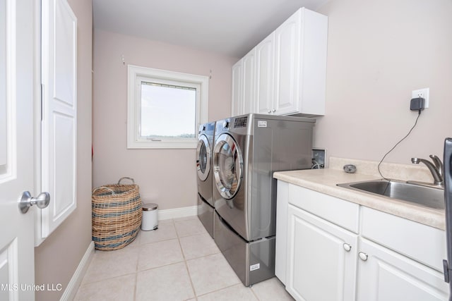 washroom with cabinet space, a sink, baseboards, light tile patterned floors, and washer and clothes dryer