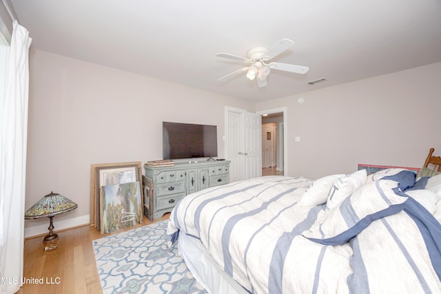 bedroom featuring baseboards, a ceiling fan, light wood-style flooring, and visible vents
