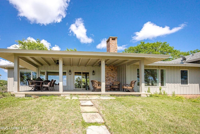 back of property featuring a lawn, ceiling fan, and a chimney