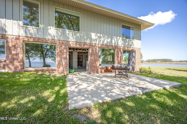 rear view of house featuring a yard, a patio area, and brick siding