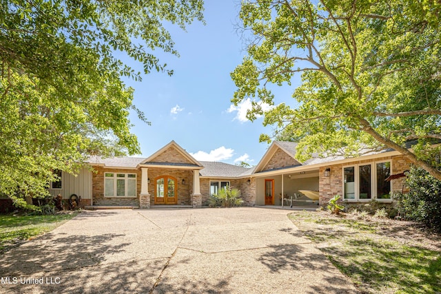 ranch-style home with driveway, french doors, and stone siding
