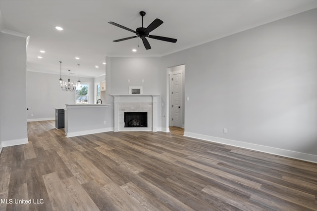 unfurnished living room with ornamental molding, wood-type flooring, and ceiling fan with notable chandelier