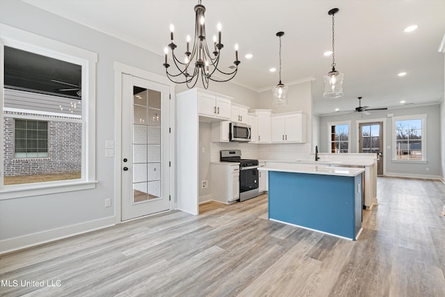 kitchen with light hardwood / wood-style flooring, ornamental molding, white cabinets, decorative light fixtures, and appliances with stainless steel finishes