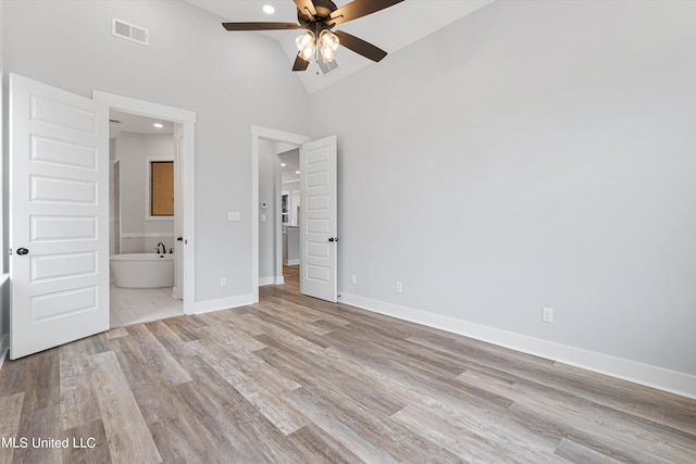 unfurnished bedroom with light hardwood / wood-style flooring, ceiling fan, high vaulted ceiling, and ensuite bath