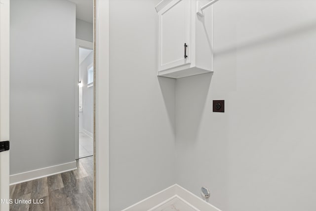 washroom featuring electric dryer hookup, cabinets, and dark hardwood / wood-style floors