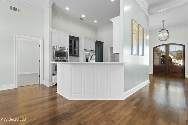 kitchen with white cabinetry, crown molding, kitchen peninsula, and a notable chandelier