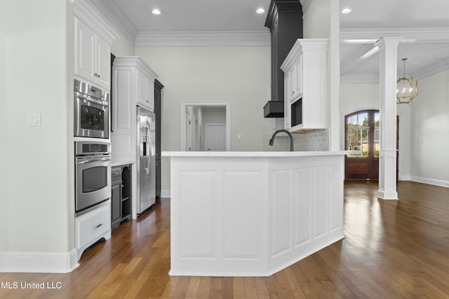 kitchen with appliances with stainless steel finishes, a chandelier, crown molding, and white cabinets