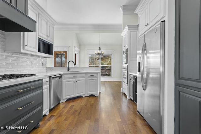 kitchen featuring decorative light fixtures, white cabinets, stainless steel appliances, and range hood