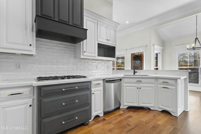 kitchen featuring white cabinets, appliances with stainless steel finishes, sink, hanging light fixtures, and kitchen peninsula