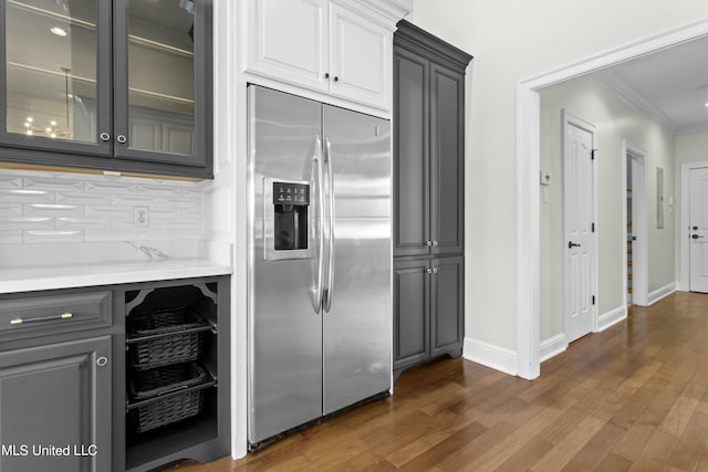 kitchen featuring tasteful backsplash, dark hardwood / wood-style floors, stainless steel fridge, ornamental molding, and gray cabinetry