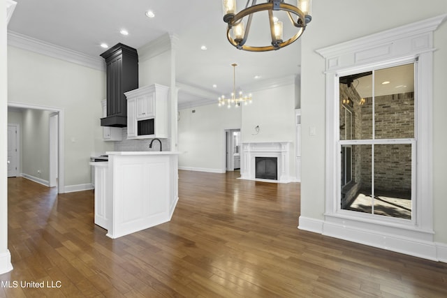 kitchen featuring backsplash, pendant lighting, sink, white cabinets, and a chandelier