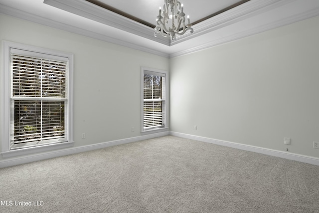 carpeted empty room featuring a healthy amount of sunlight, crown molding, and a raised ceiling