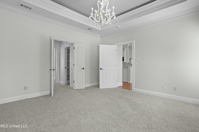 unfurnished bedroom featuring crown molding, carpet floors, a tray ceiling, and a notable chandelier