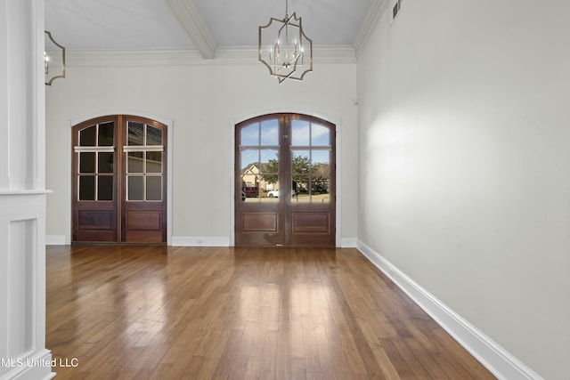 foyer entrance with hardwood / wood-style floors, ornamental molding, french doors, and an inviting chandelier