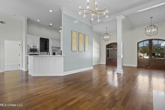 unfurnished living room featuring a high ceiling, ornate columns, french doors, dark hardwood / wood-style floors, and crown molding