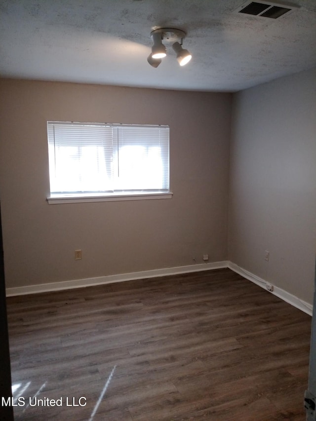 unfurnished room featuring a textured ceiling and dark wood-type flooring