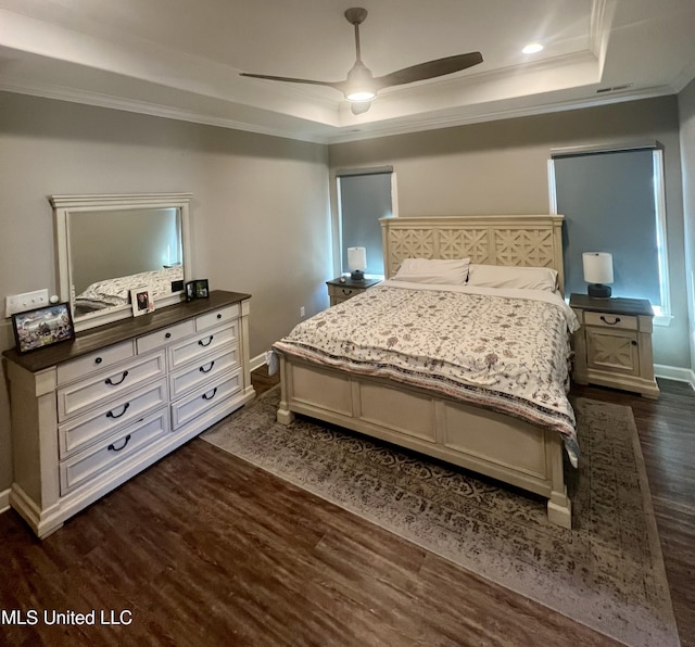 bedroom with a tray ceiling, ornamental molding, dark hardwood / wood-style floors, and ceiling fan